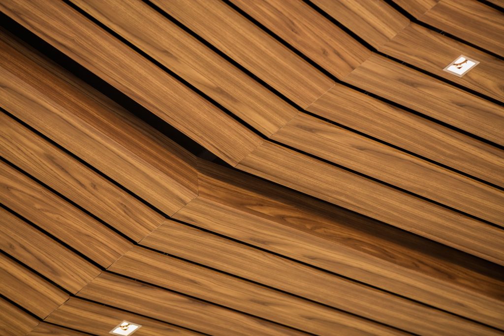 Customized metal ceiling elements in wood finishes create a warm, natural look.